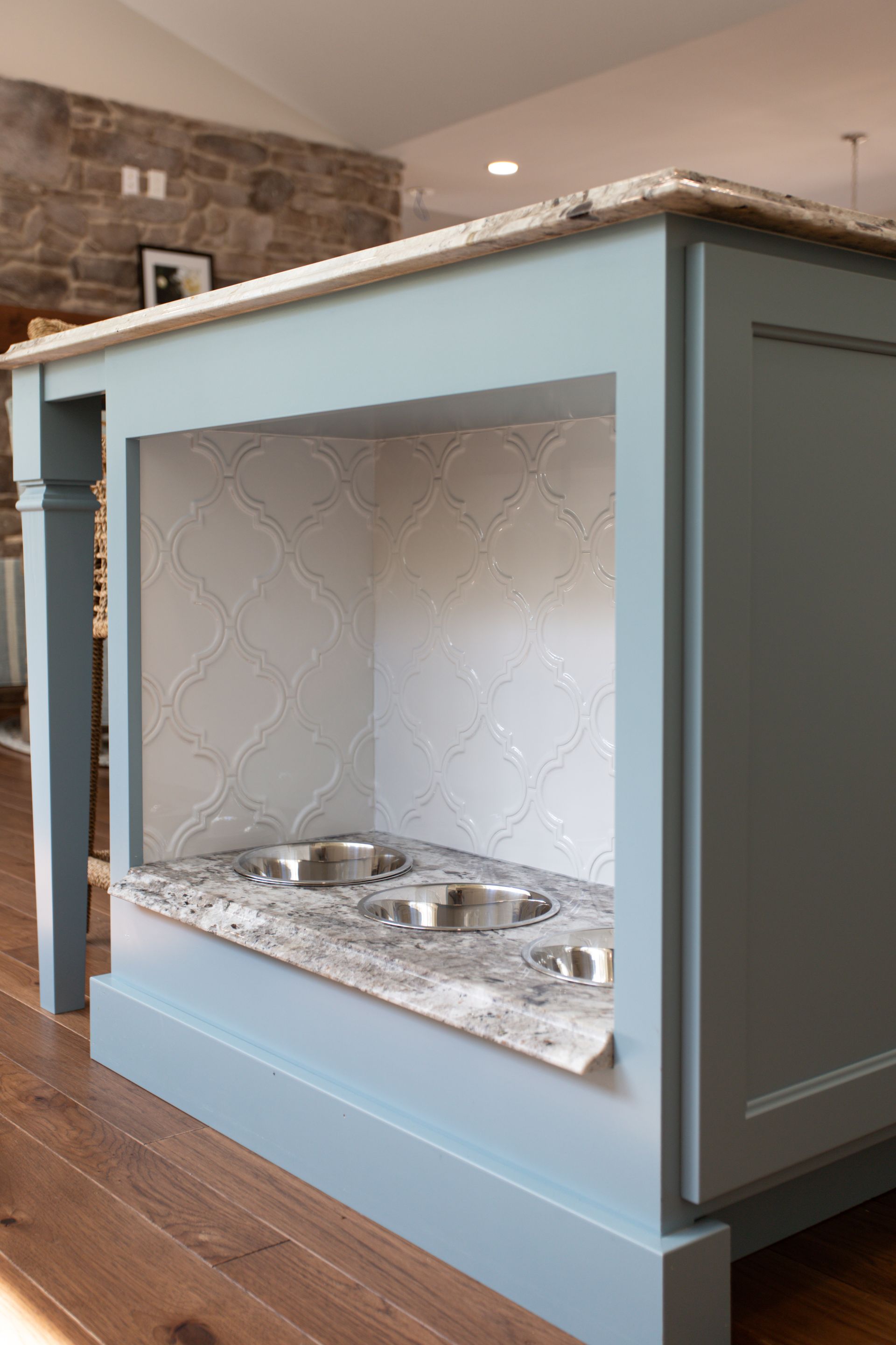 Light blue kitchen island with built-in fireplace opening and stone countertop in a modern home.
