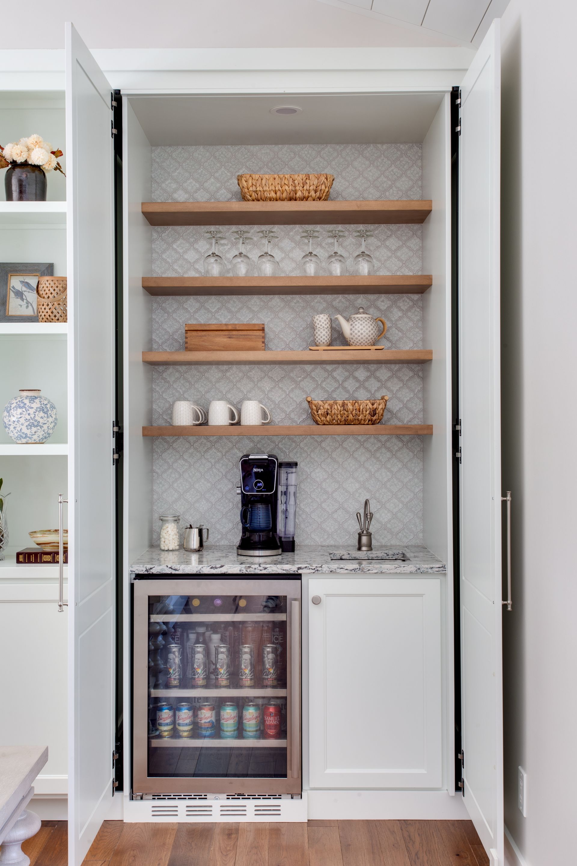 Built-in beverage bar with open shelves, mini fridge, and white cabinet doors in a kitchen alcove.