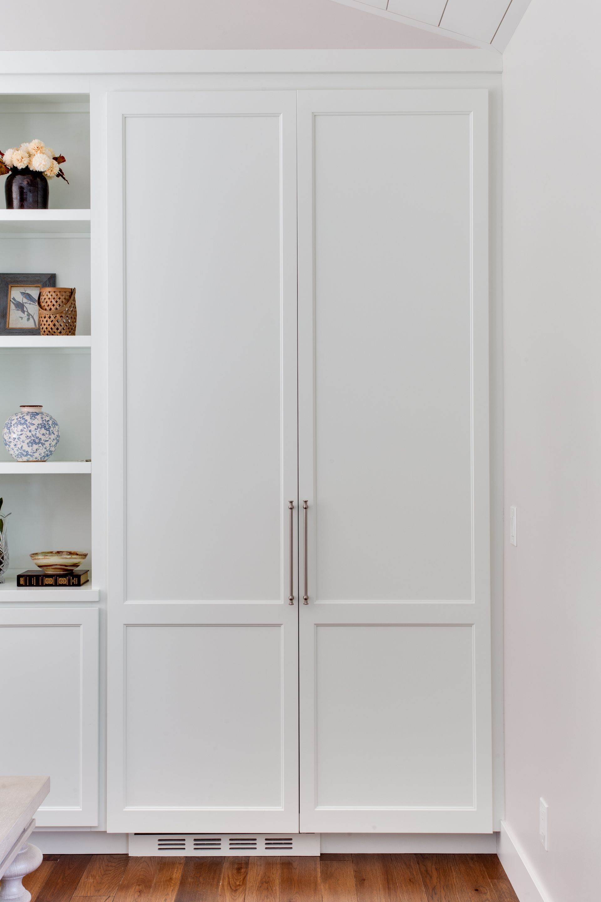 White built-in closet doors in a bedroom, with shelves visible on the left.
