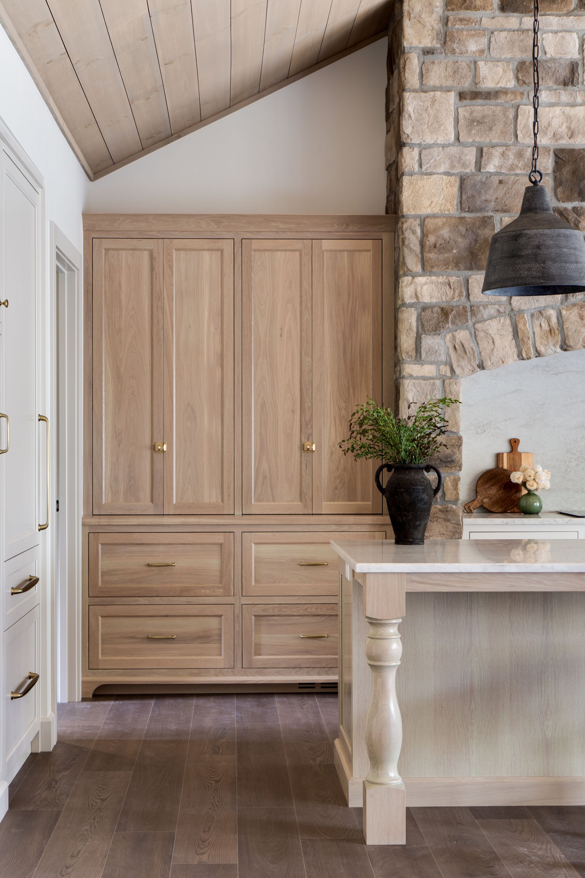 Built-in wood cabinets beside a stone fireplace and white table in a rustic room.