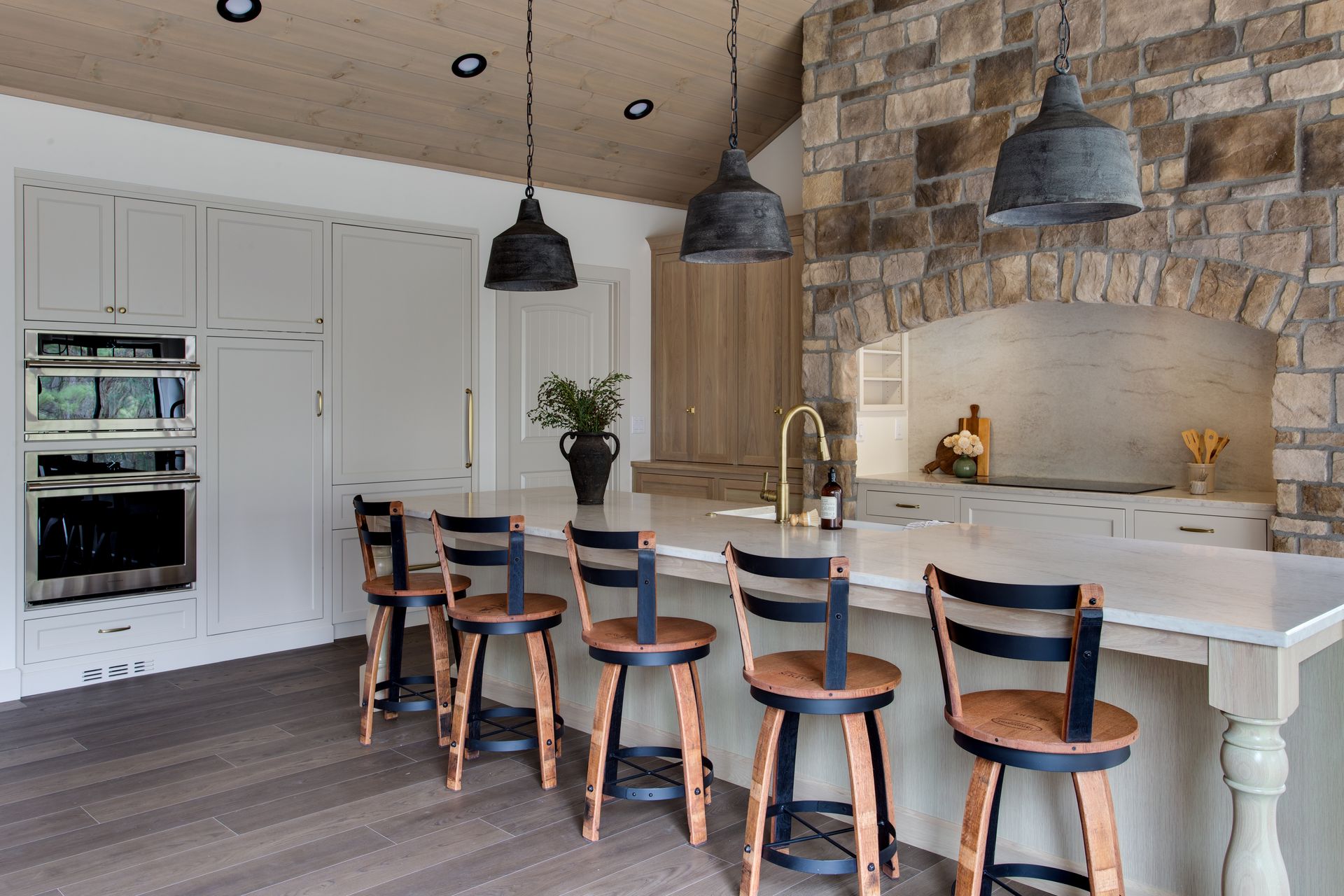 Modern kitchen with island, bar stools, white cabinets, wood ceiling, and pendant lights.