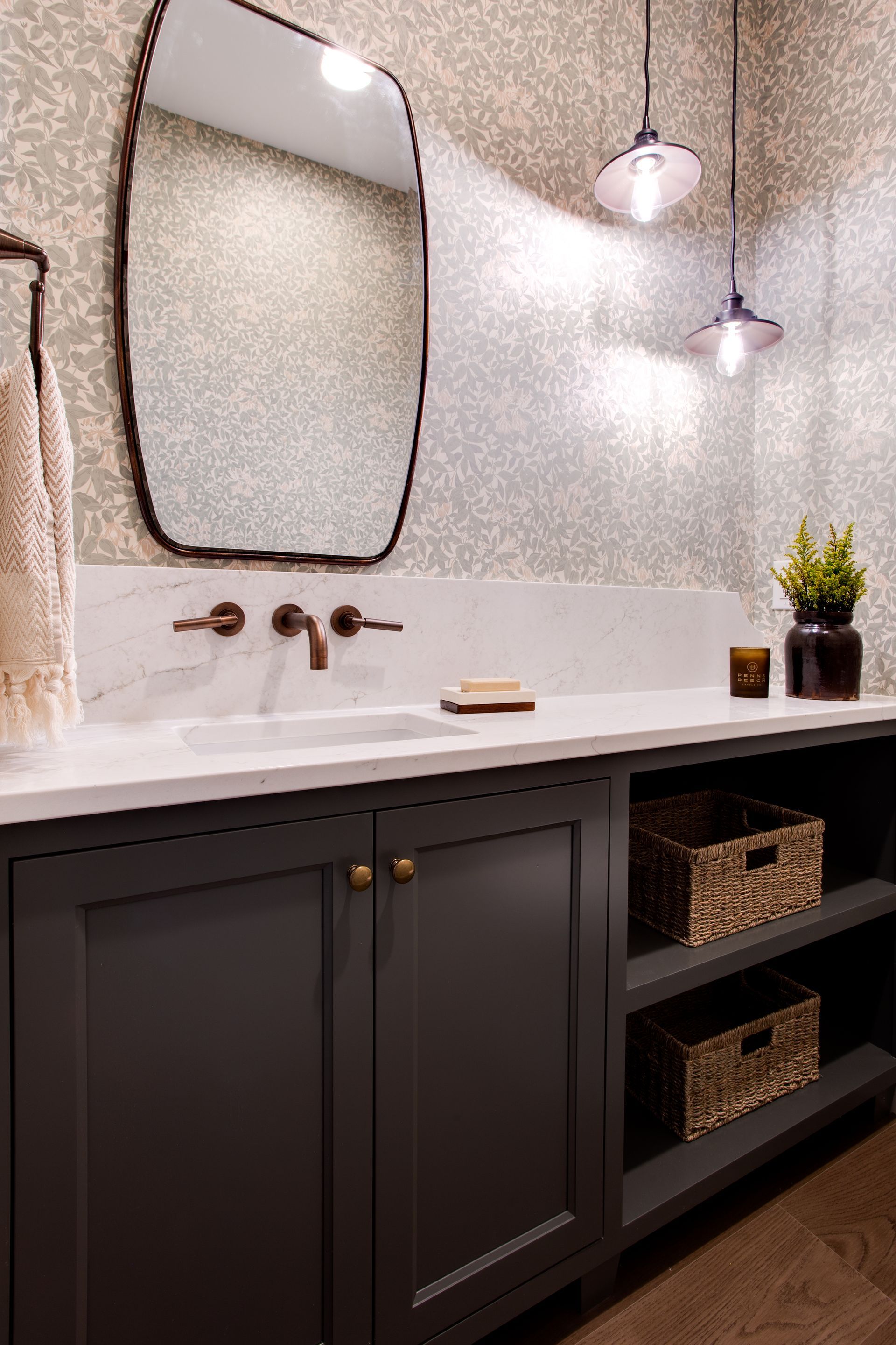 Modern bathroom vanity with black cabinets, white countertop, mirror, and hanging pendant lights.