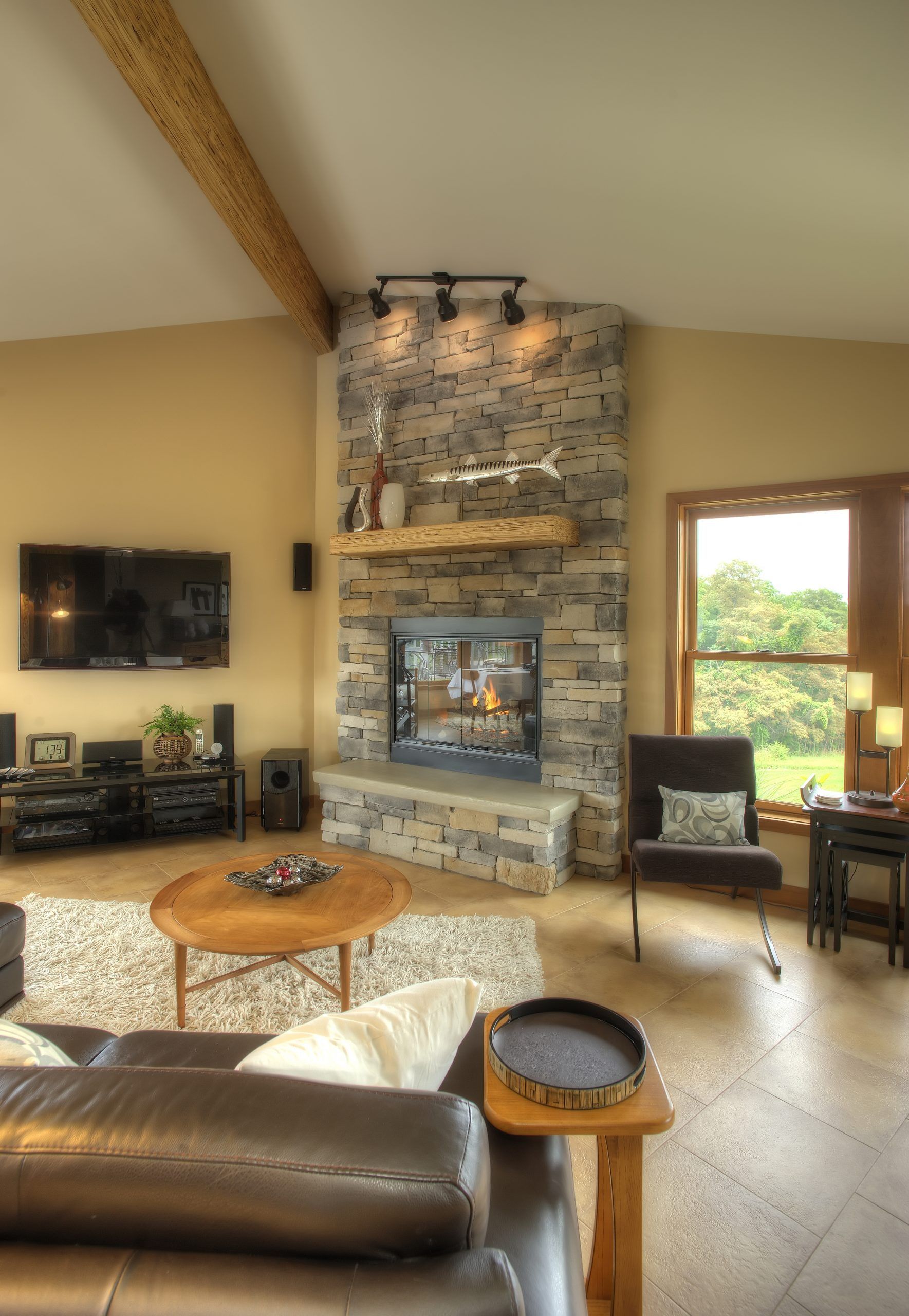 A living room with a stone fireplace and a flat screen tv.