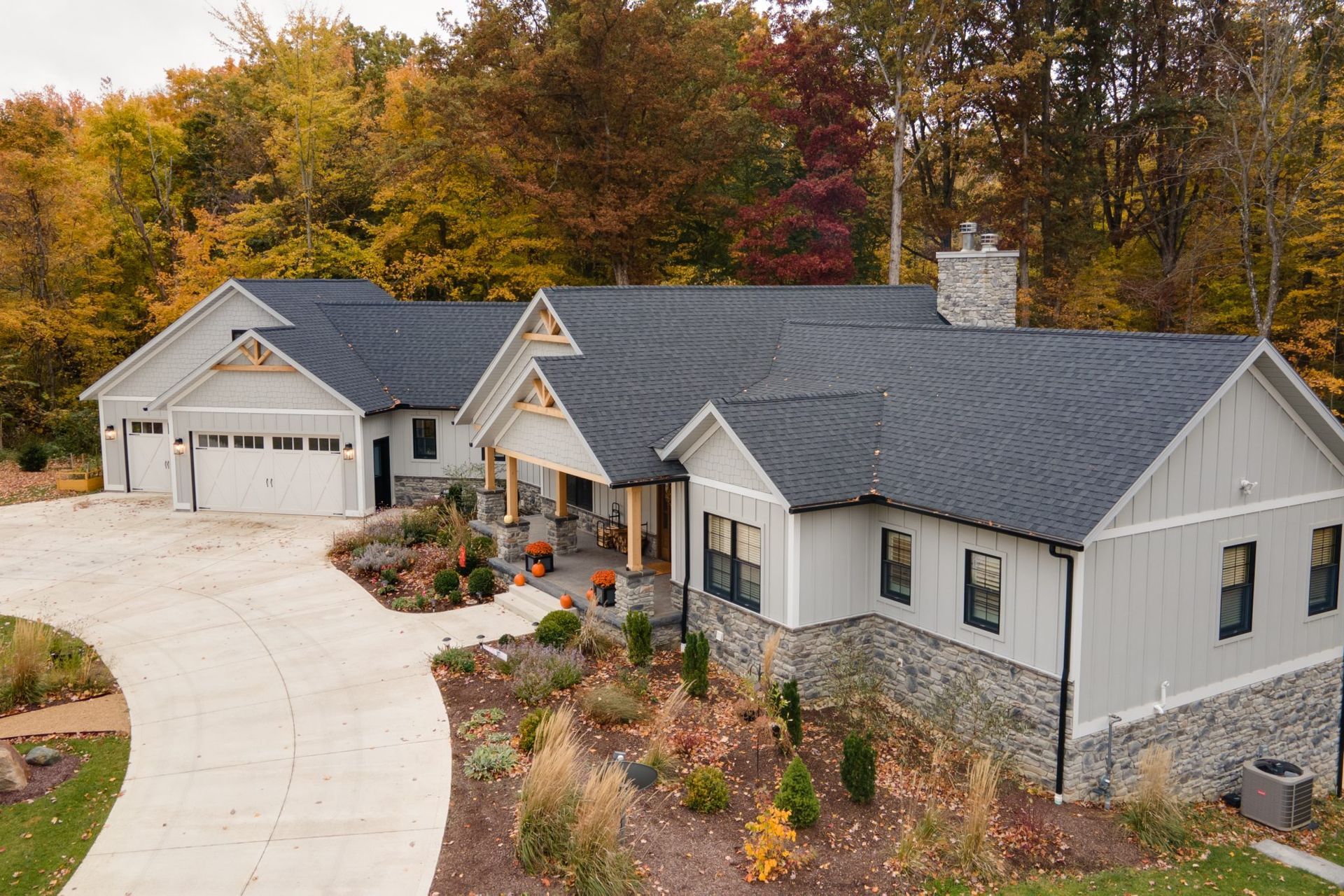 An aerial view of a large white house with a black roof surrounded by trees.