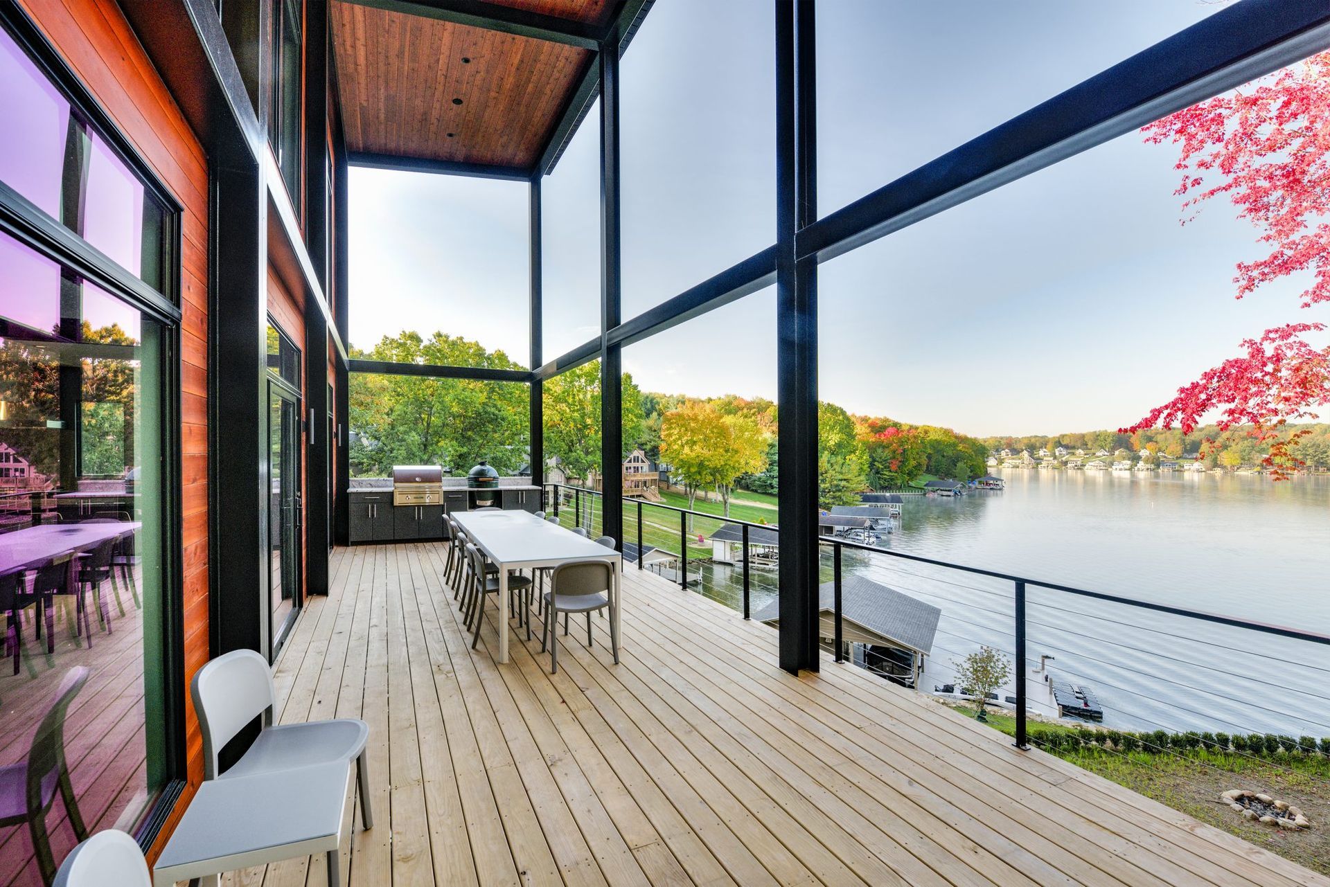 A large deck with a table and chairs overlooking a lake.