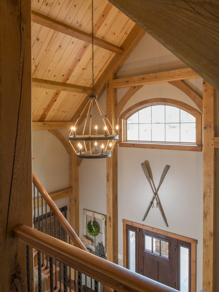 A wooden staircase with a chandelier hanging from the ceiling.