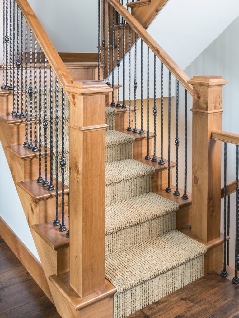 A wooden staircase with a wrought iron railing and a carpeted staircase.