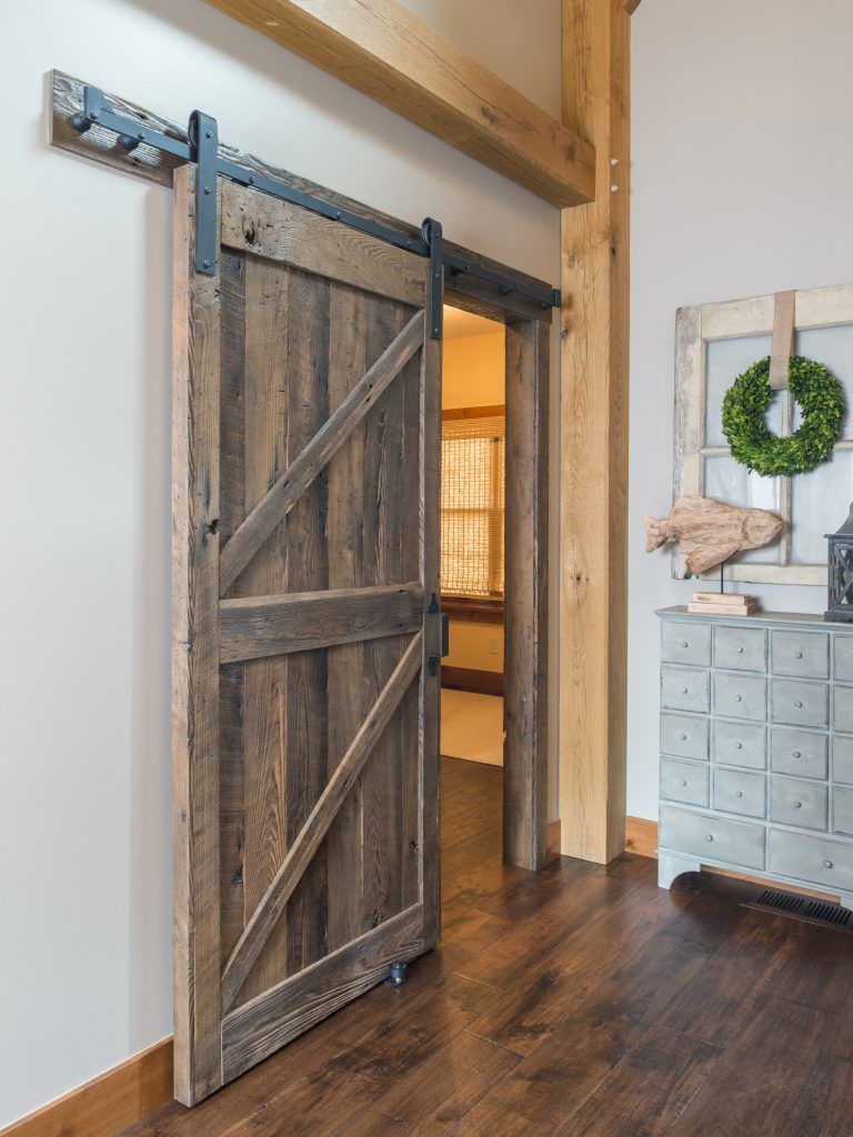A wooden sliding barn door is open in a hallway.