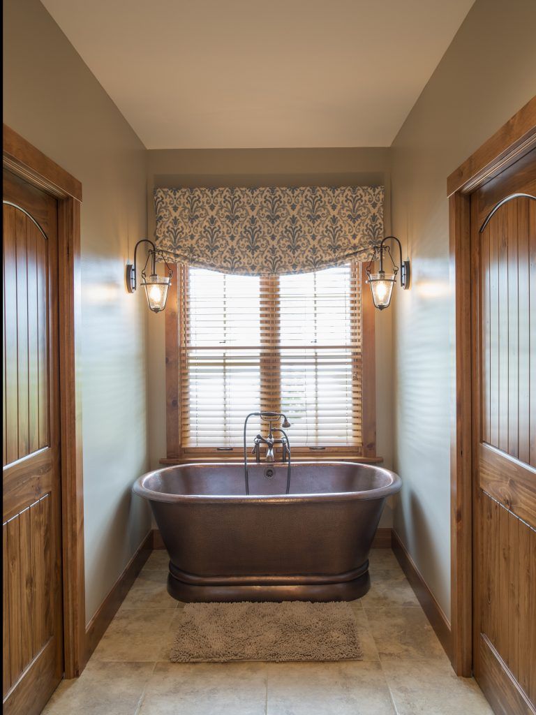 A bathroom with a tub and a window with blinds.