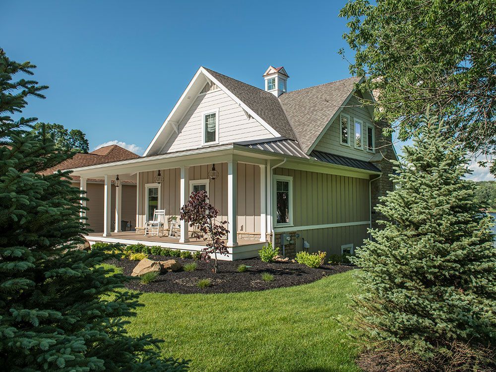 A large house with a large porch and trees in front of it.