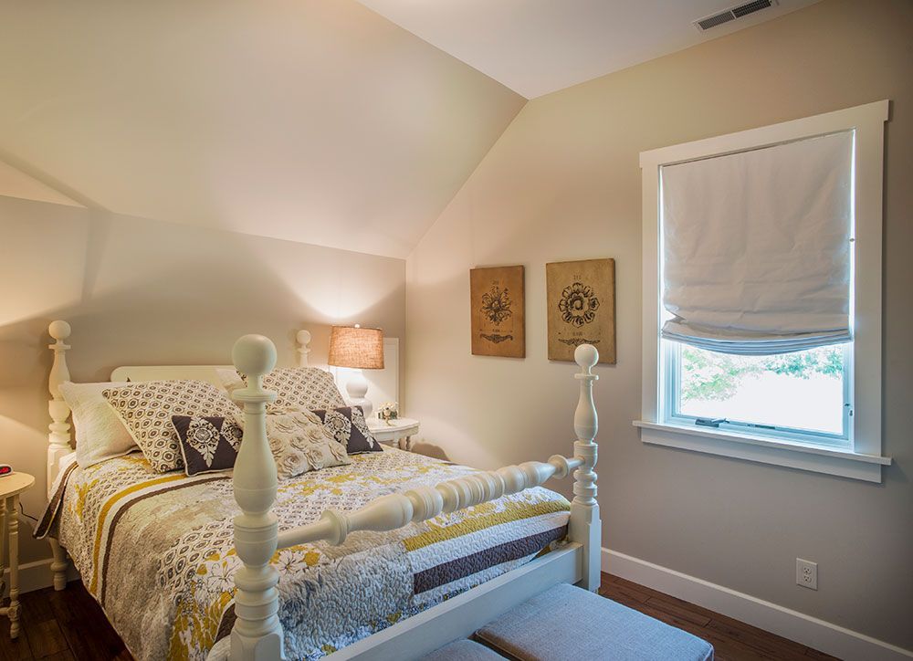 A bedroom with a white bed and a window.
