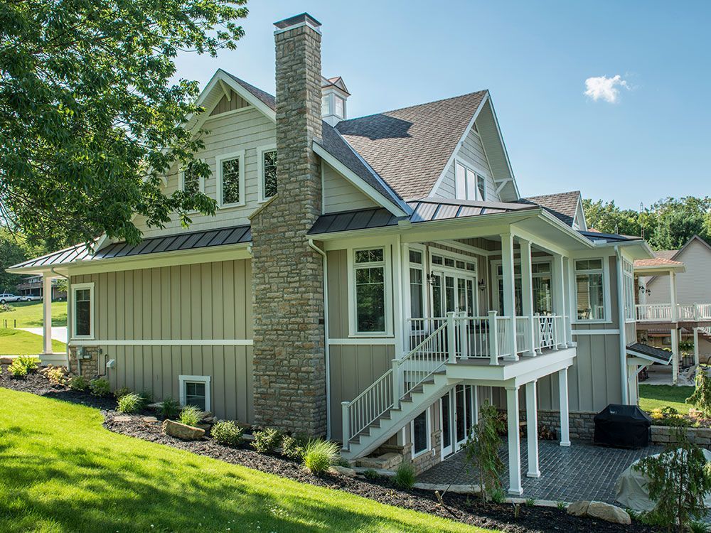 The back of a large house with a large porch and stairs.