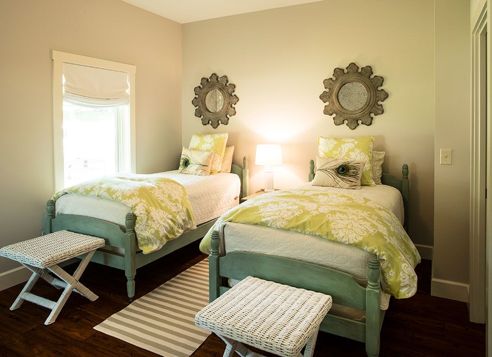 A bedroom with two twin beds and two ottomans.