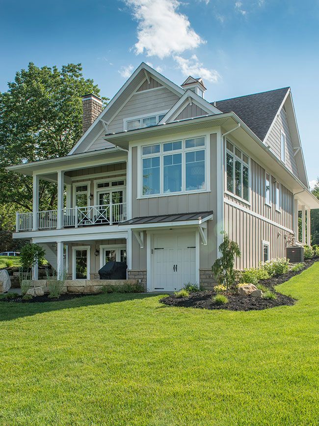 A large house with a lot of windows is sitting on top of a lush green lawn.