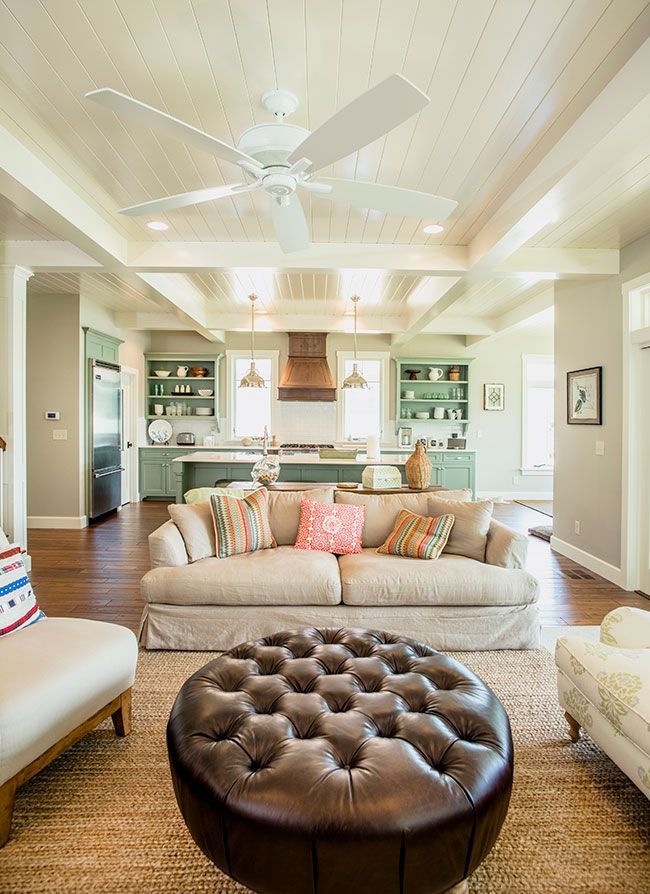 A living room with a couch, ottoman, chairs, and a ceiling fan.