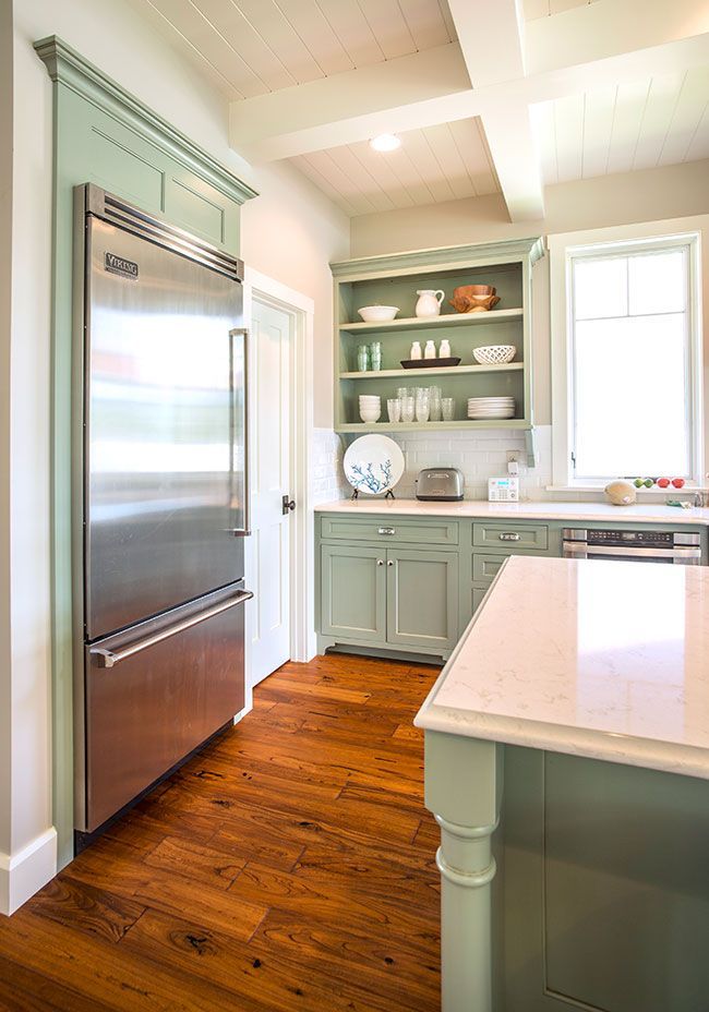 A kitchen with stainless steel appliances and green cabinets.