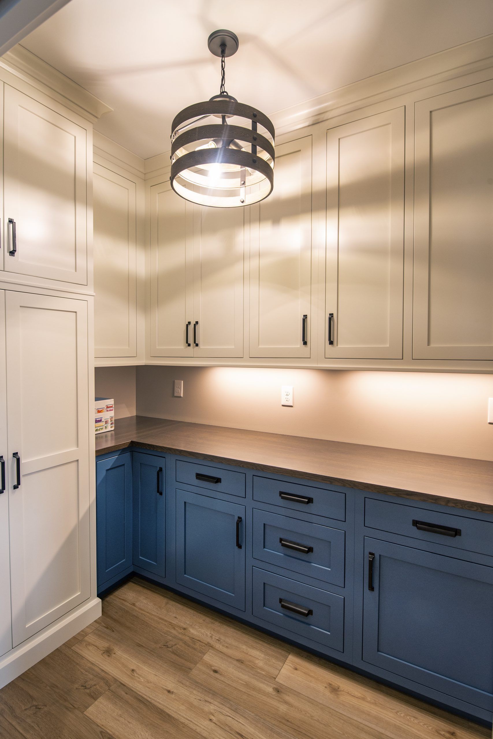 A kitchen with blue cabinets and white cabinets and a light hanging from the ceiling.