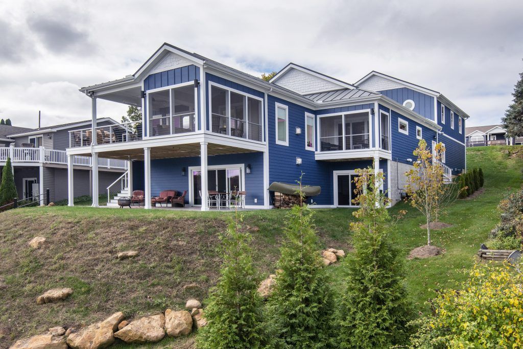 A large blue house is sitting on top of a grassy hill.