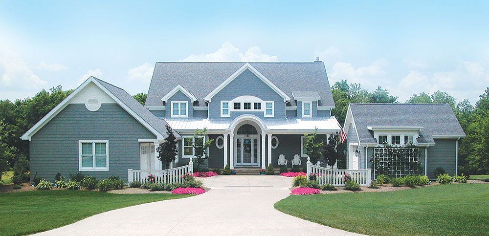 A large light blue house with a driveway leading to it.
