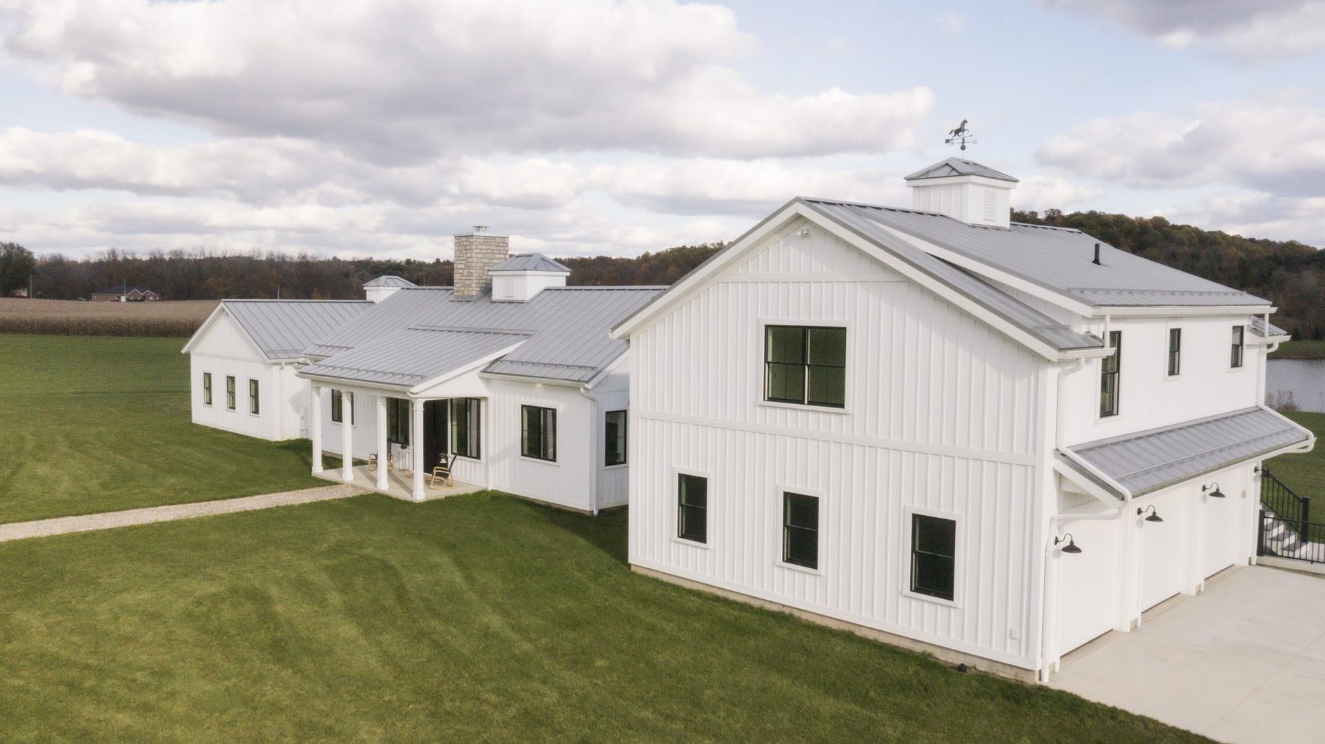 A large white house is sitting on top of a lush green field.