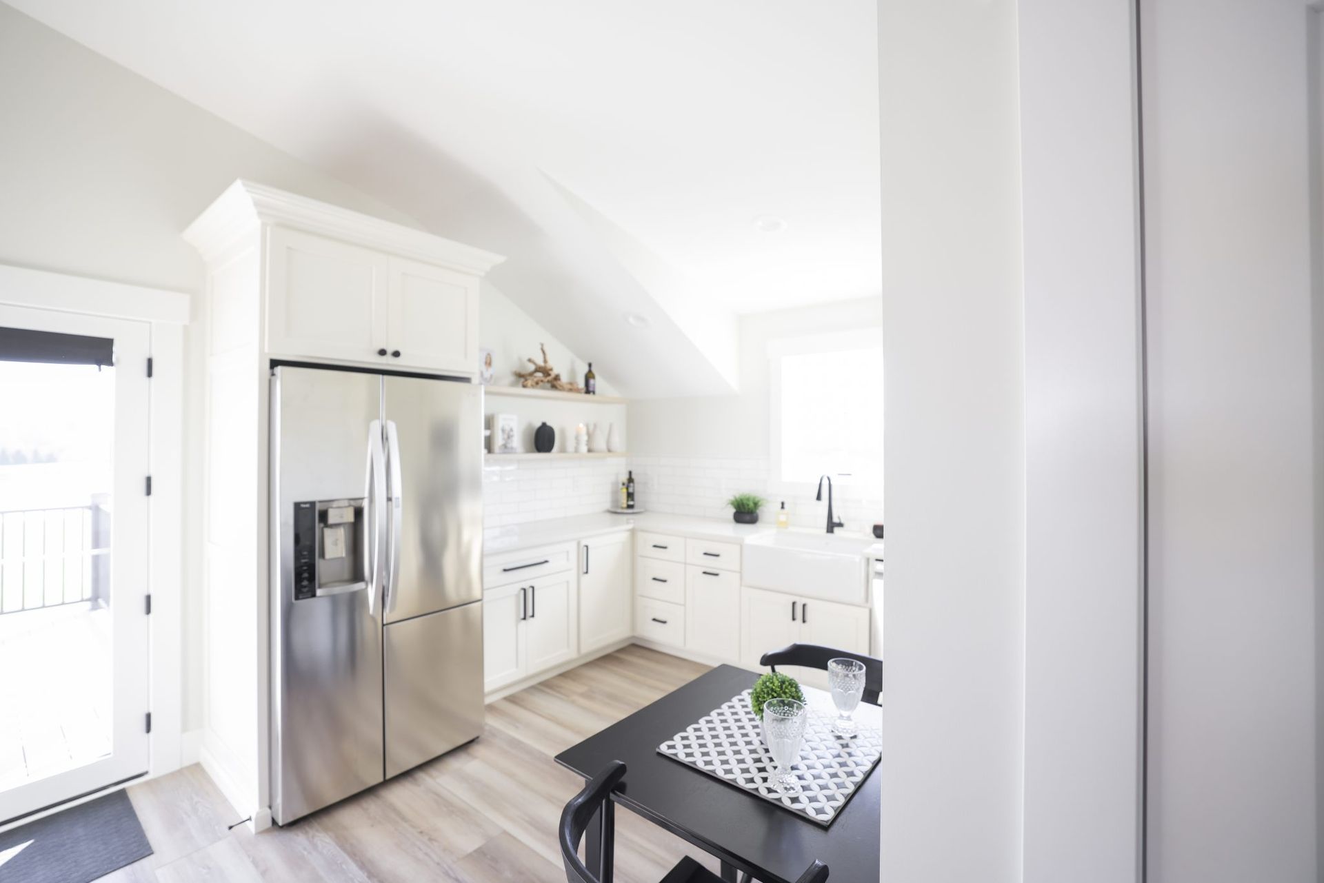 A kitchen with white cabinets and a stainless steel refrigerator.
