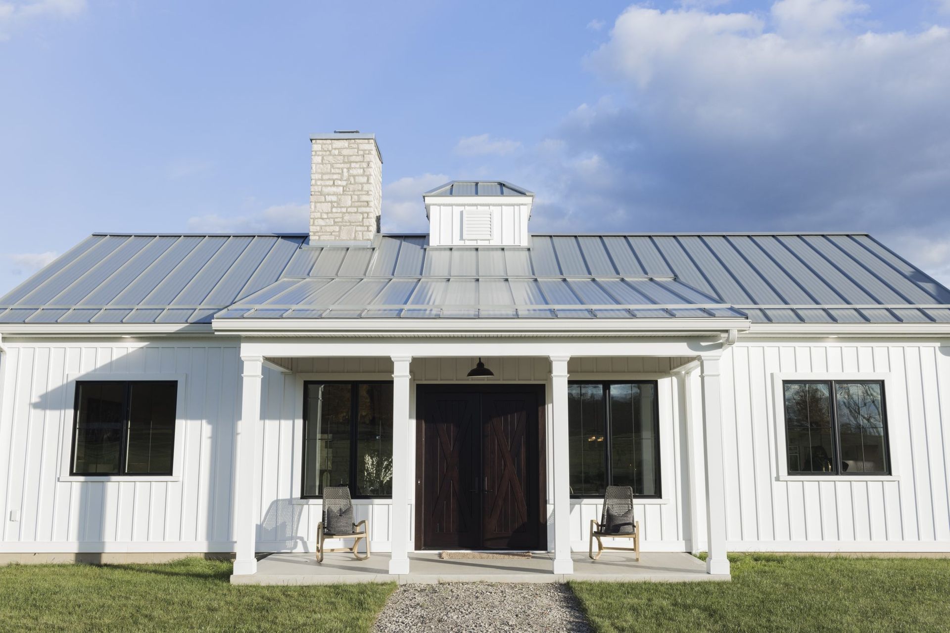 A white house with a metal roof and a porch.