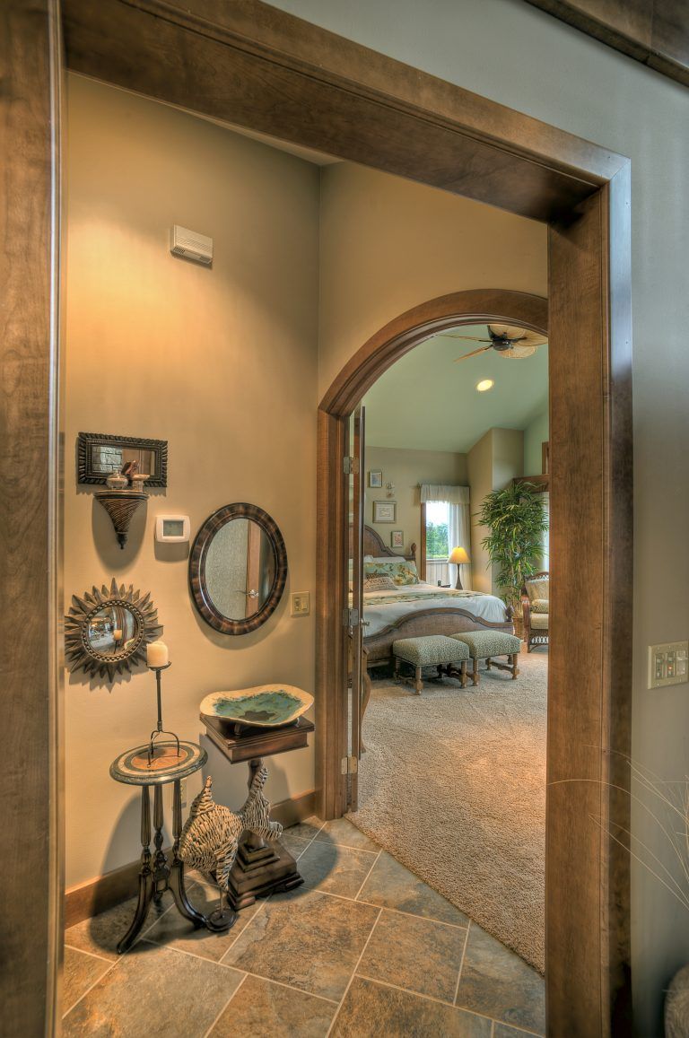 A hallway with a wooden archway leading to a bedroom.