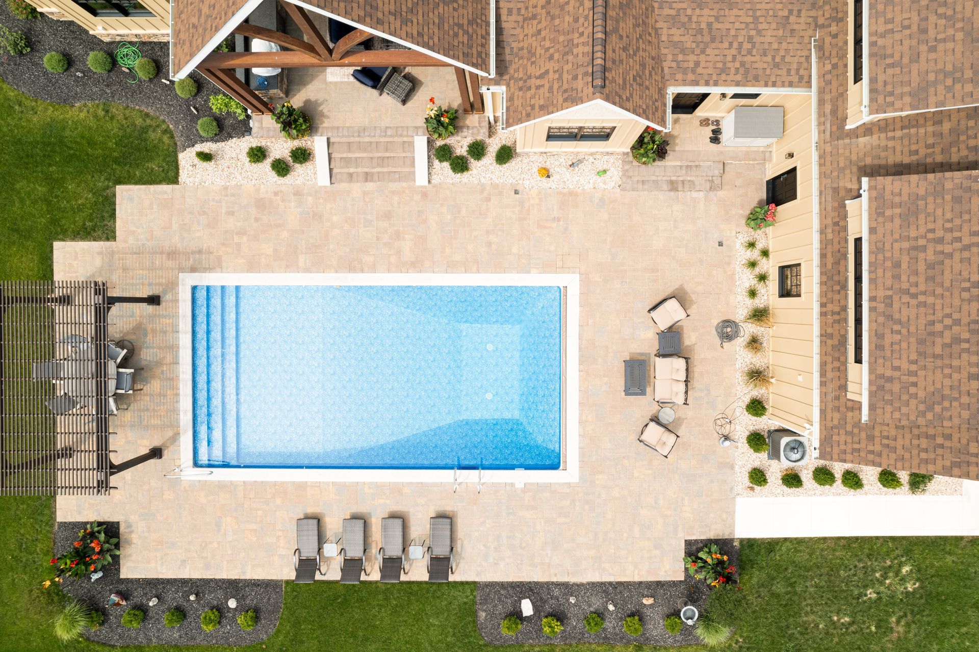 An aerial view of a large swimming pool in the backyard of a house.