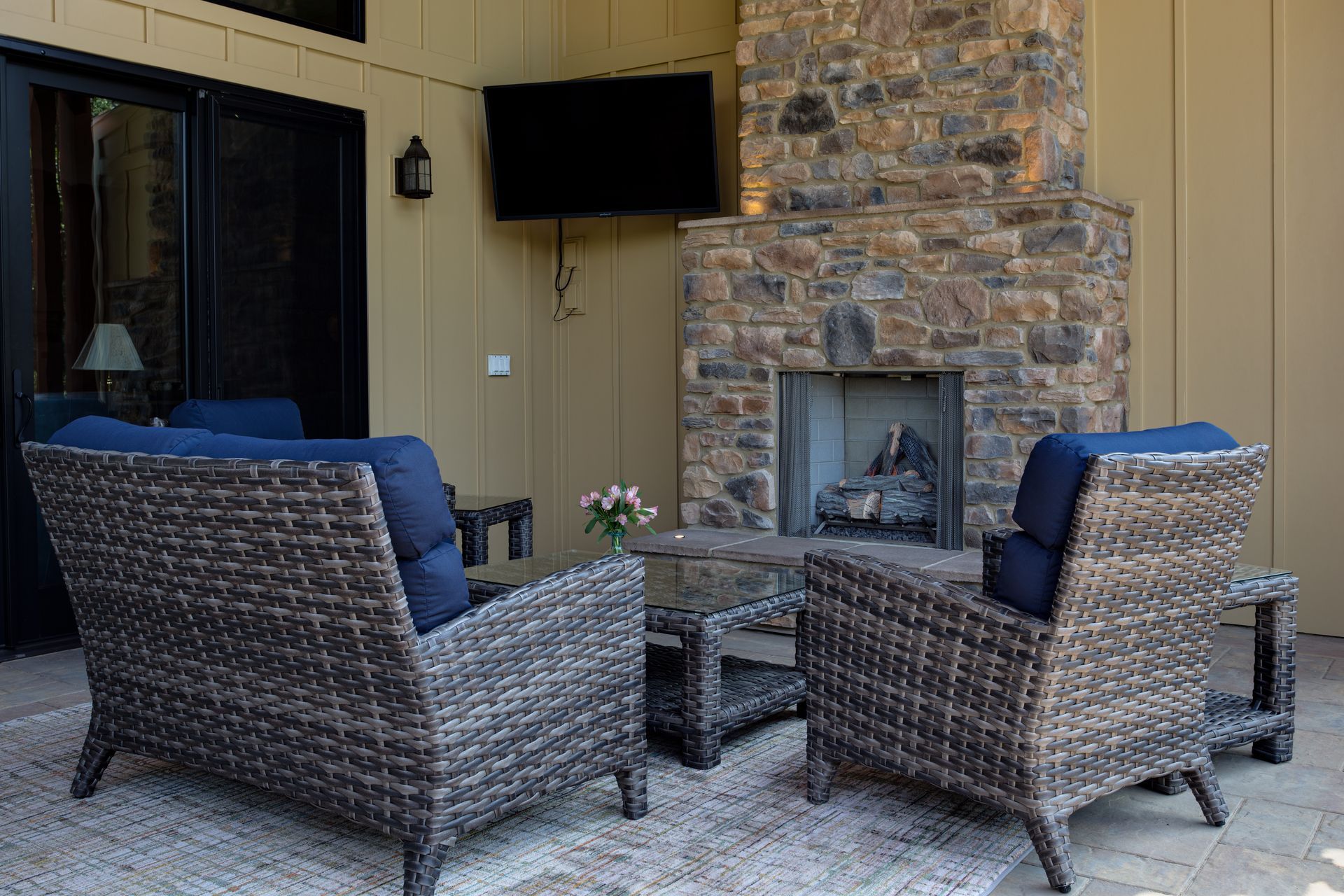 A patio with wicker furniture and a fireplace.