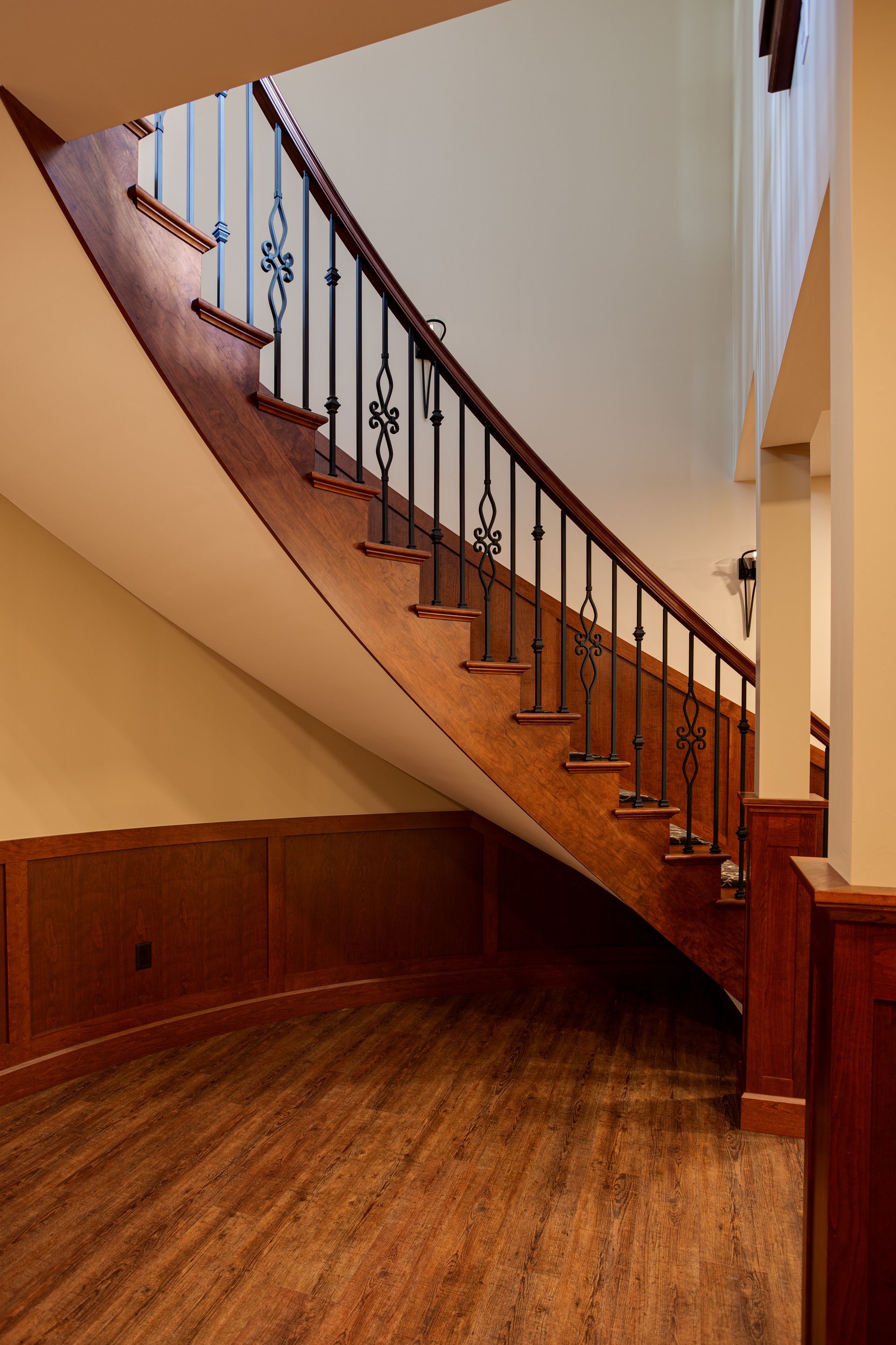 A curved wooden staircase with a wrought iron railing.