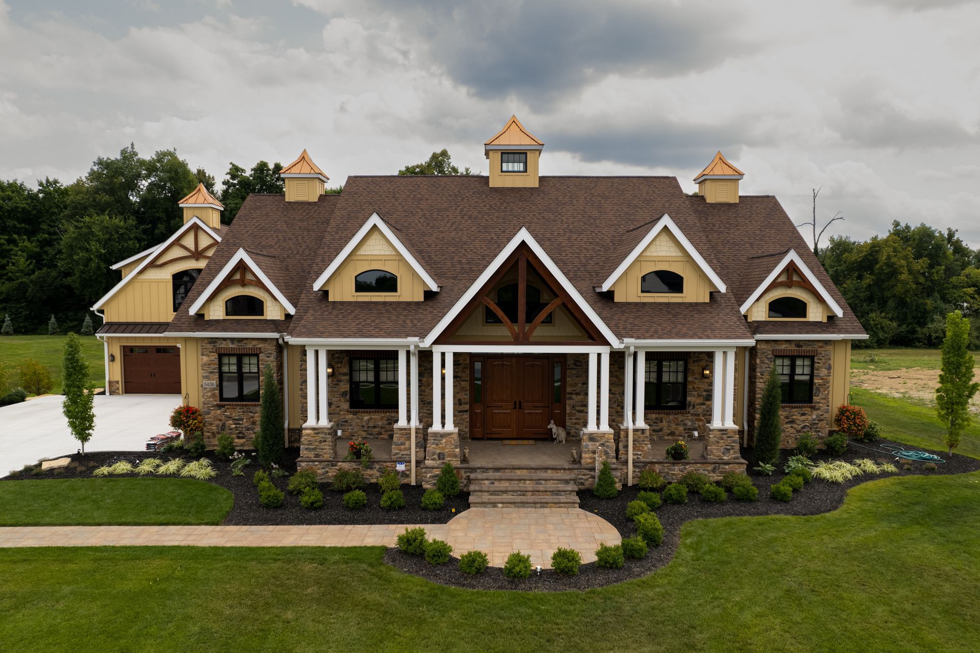 A large house with a brown roof is sitting on top of a lush green field.