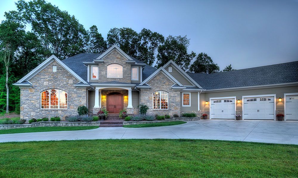 A large stone house with three garages and a driveway.