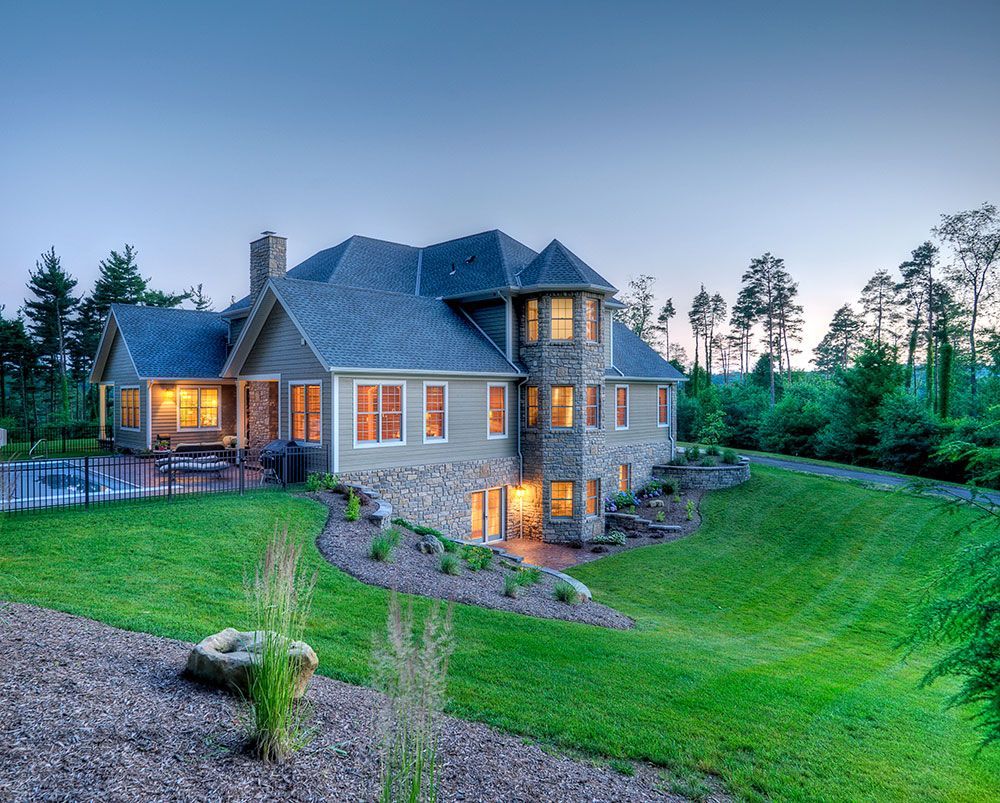 A large house sits on top of a lush green hillside.