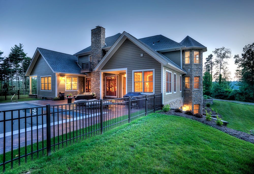 A large house with a fence around it is lit up at night.