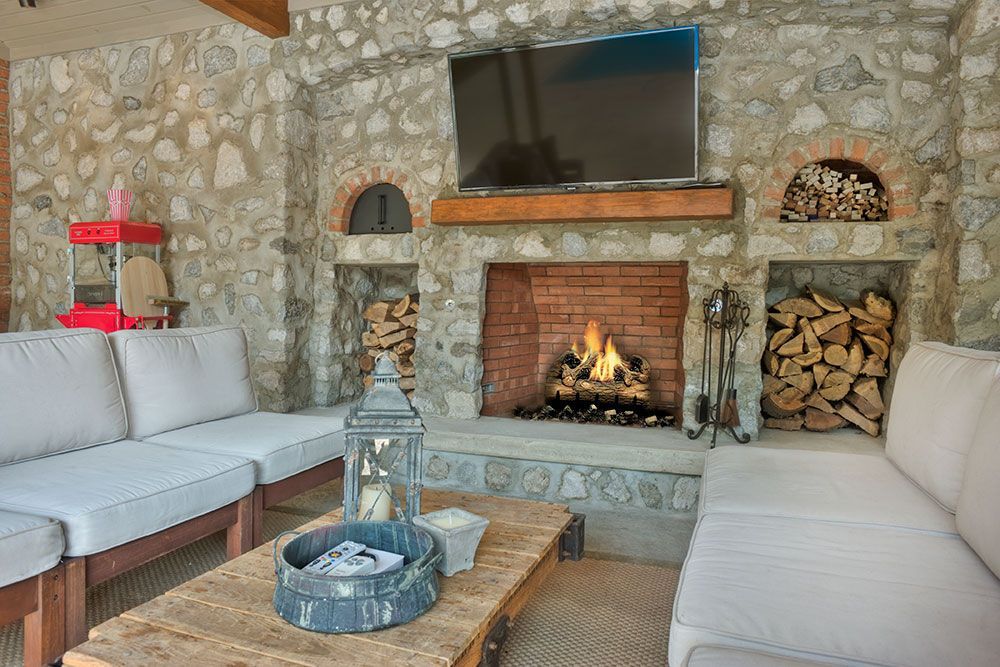 A living room with a fireplace, couch, table, and television.