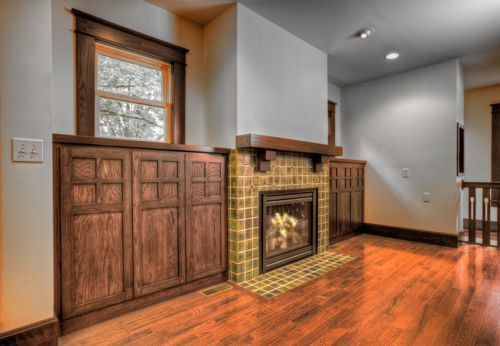 A living room with a fireplace and wooden cabinets.