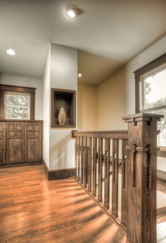 A hallway with hardwood floors and a wooden railing.