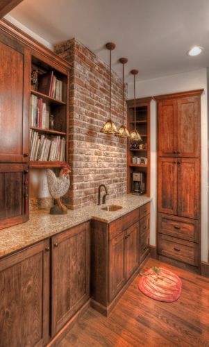 A kitchen with wooden cabinets and a brick wall.