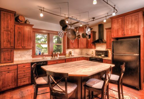 A kitchen with a table and chairs and pots hanging from the ceiling.