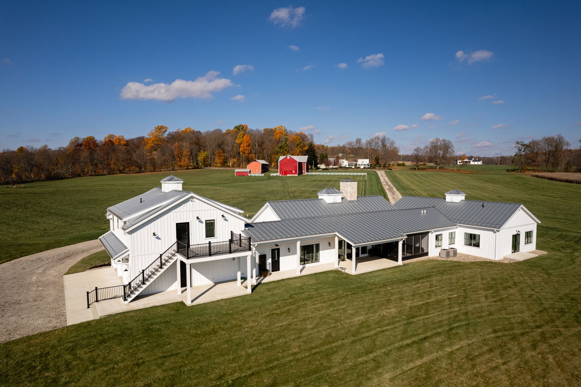 An aerial view of a large white house in the middle of a grassy field.