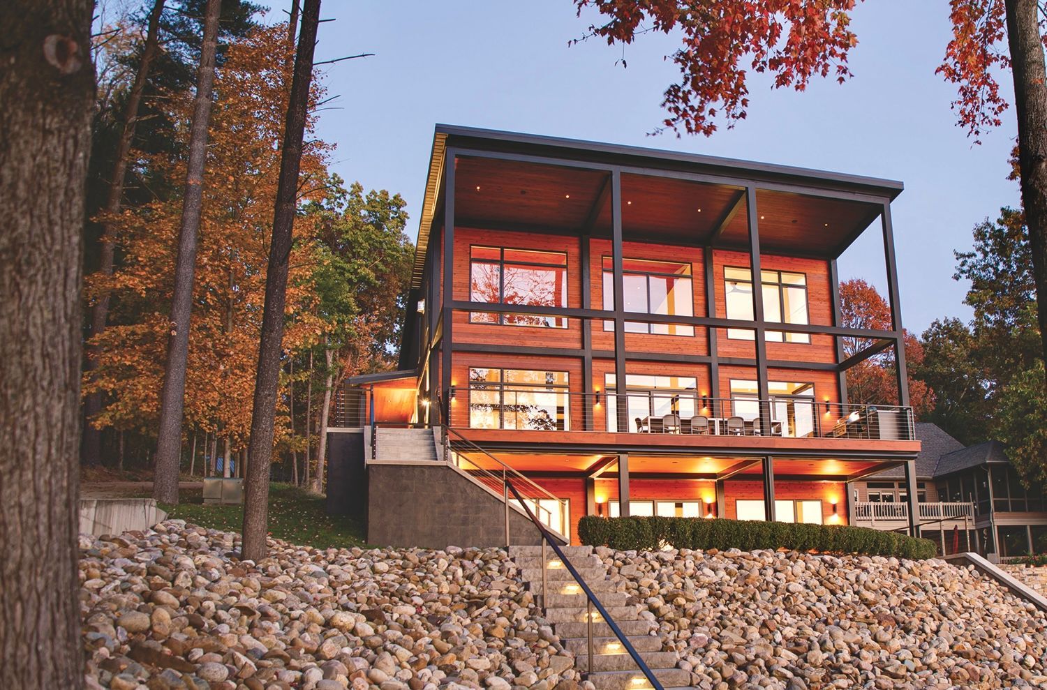 A large modern house with a lot of windows is surrounded by trees