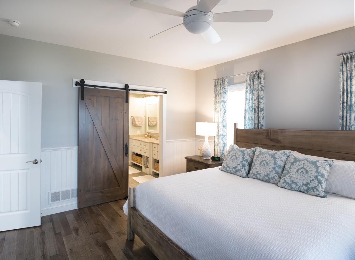 A bedroom with a king size bed and a ceiling fan.