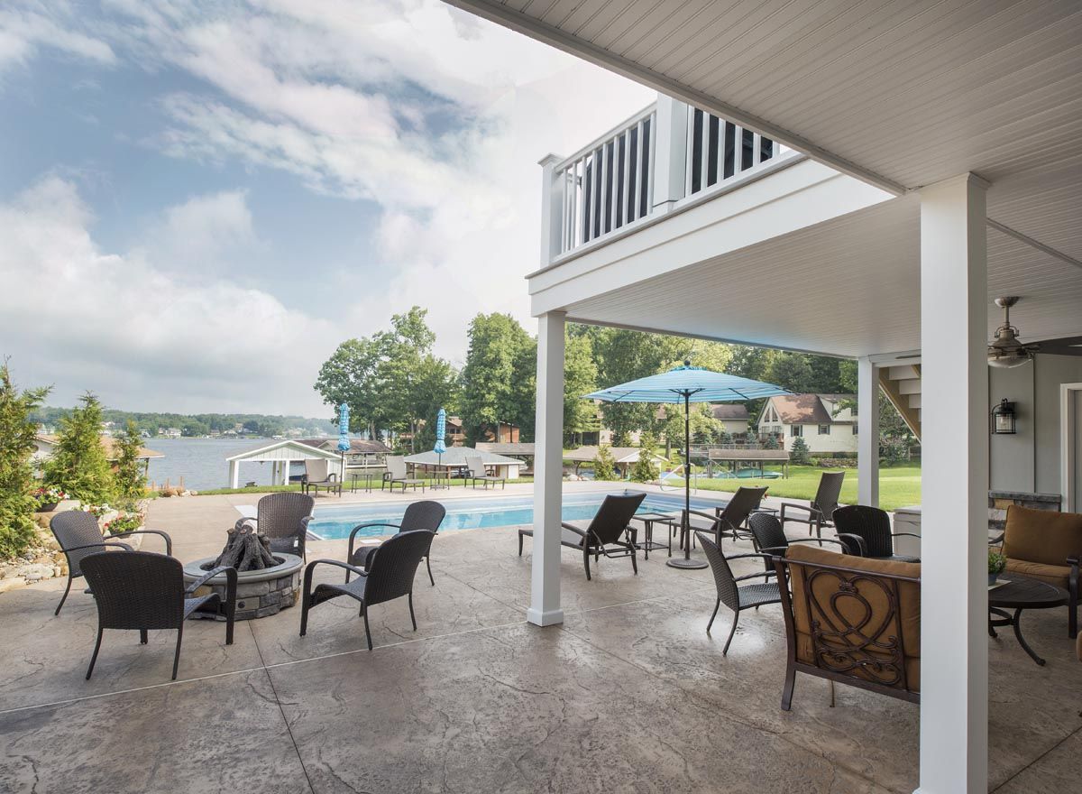 A patio with chairs and umbrellas overlooking a lake
