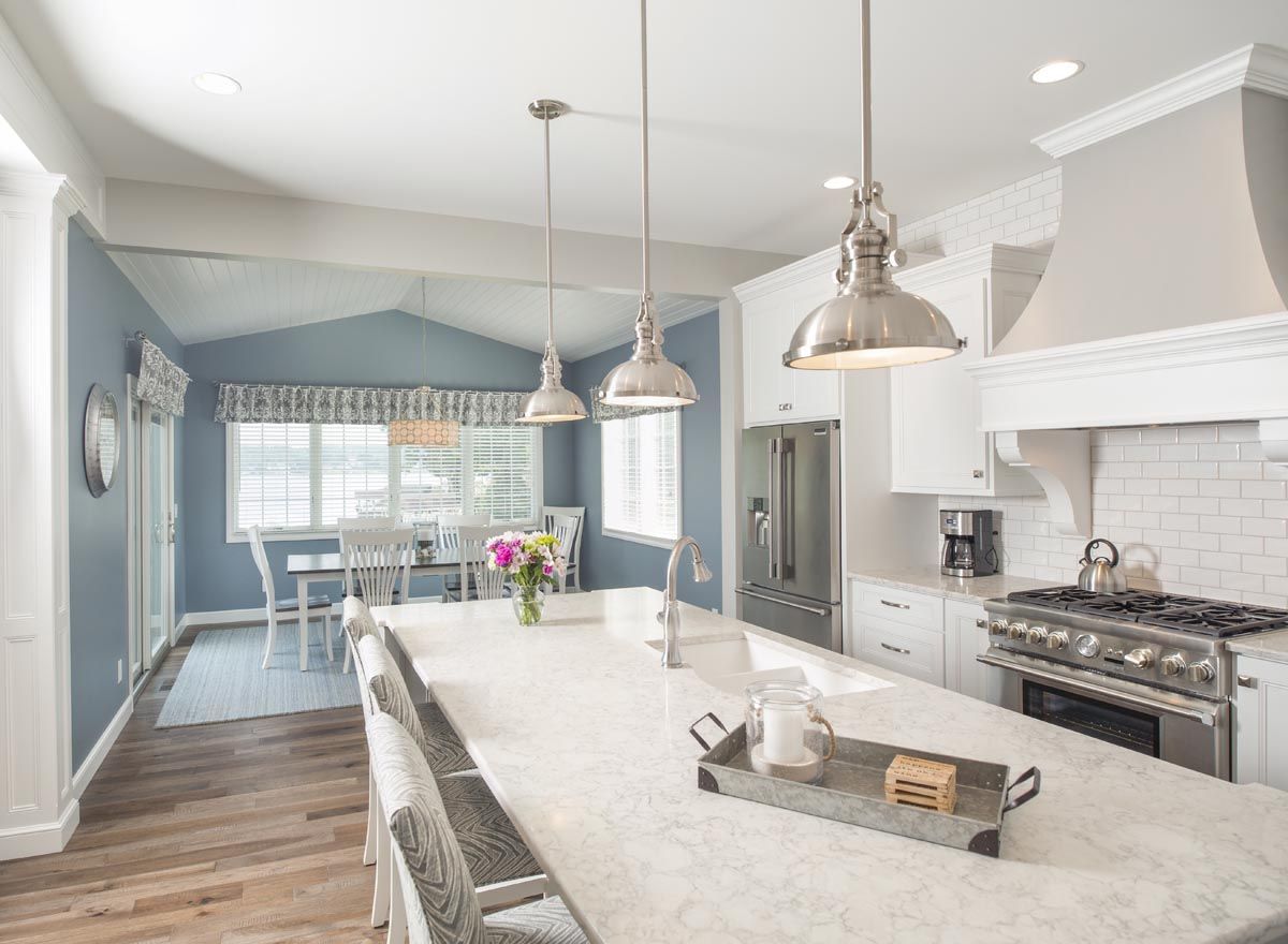 A kitchen with a large island in the middle and a dining room in the background.