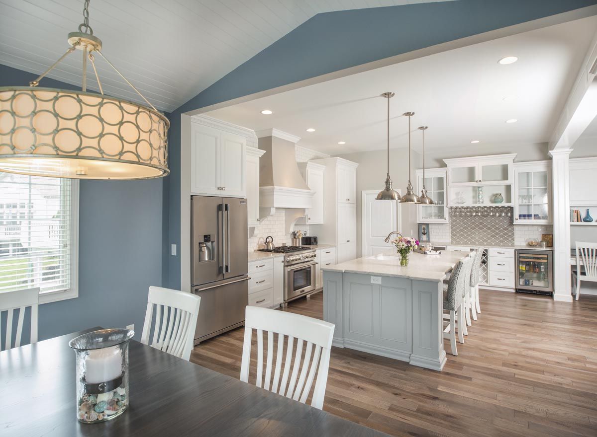 A kitchen with white cabinets and stainless steel appliances is open to a dining room.