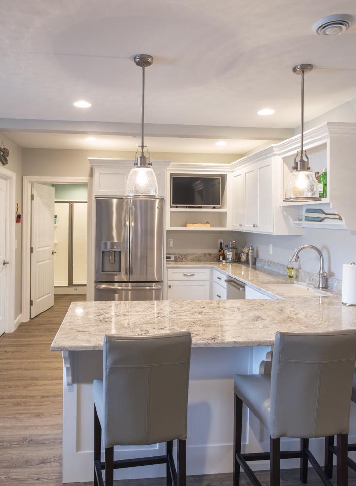A kitchen with white cabinets, granite counter tops, stainless steel appliances and refrigerator.