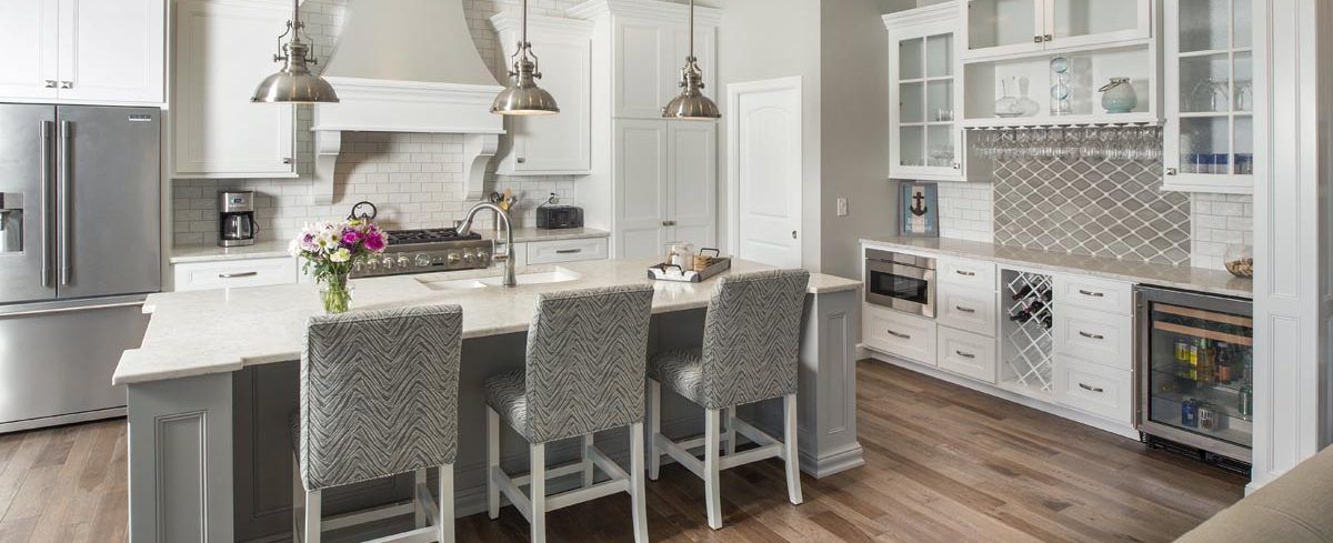 A kitchen with white cabinets, stainless steel appliances, hardwood floors, and a large island.