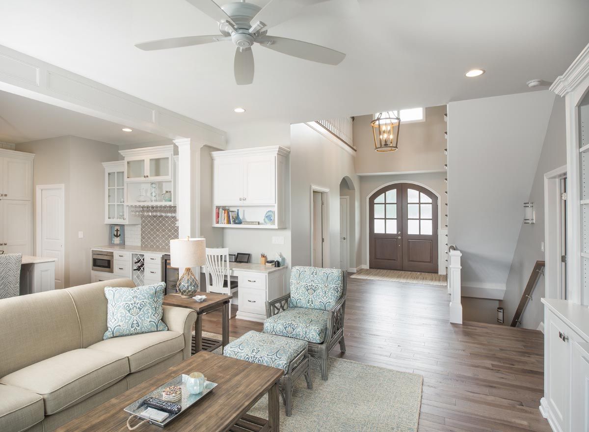 A living room with a couch, chairs, coffee table and ceiling fan.