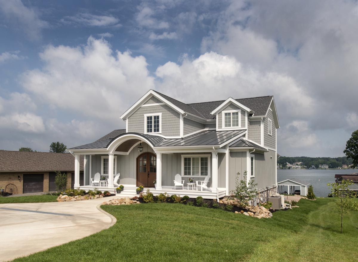 A large house with a large porch and a lake in the background