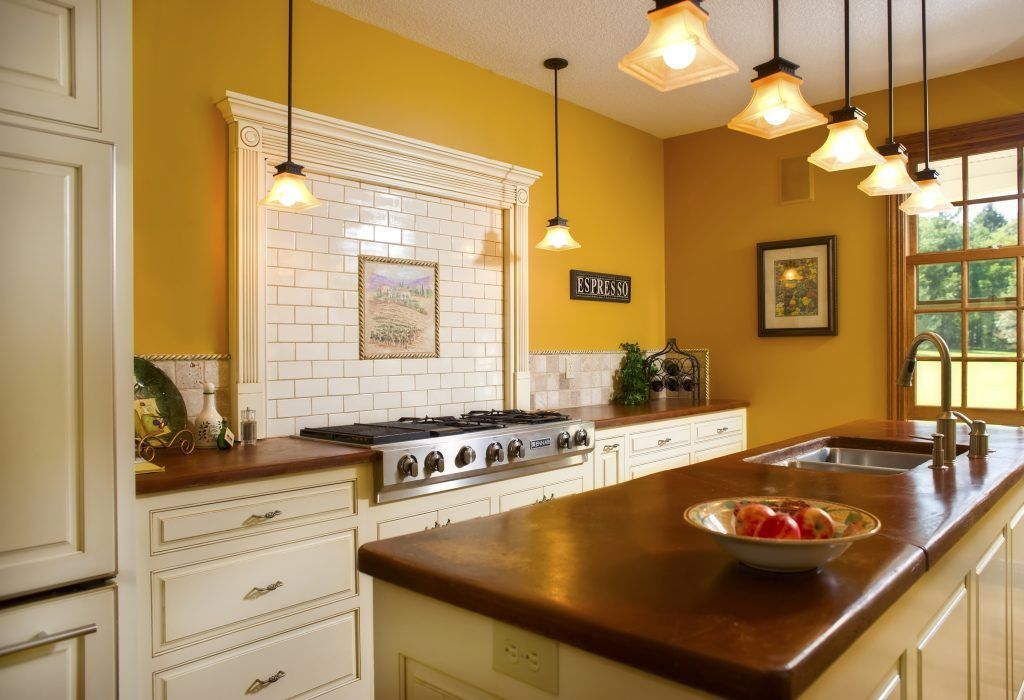 A kitchen with yellow walls and white cabinets.